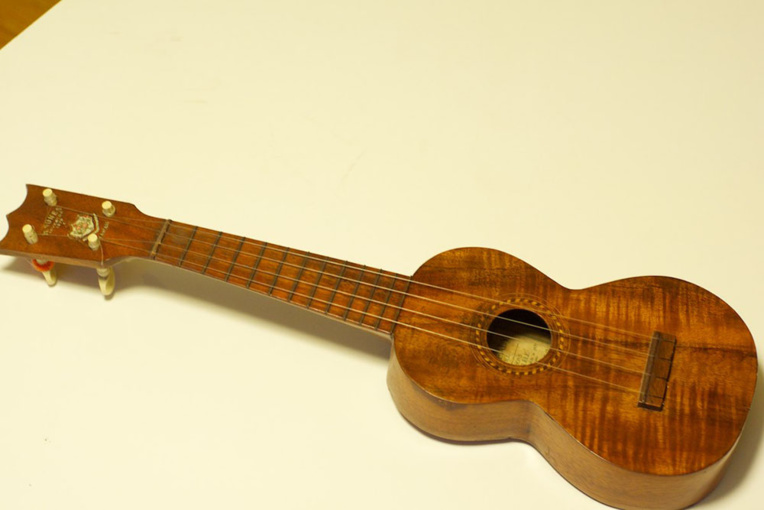 Un ukulele de la marque Nunes ; celui-ci est daté de 1916, la fabrique de Manuel Nunes et de ses fils ayant fermé ses portes en 1917.