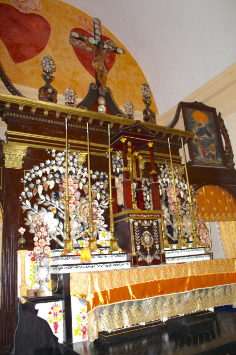 Le maître autel, fait d’une délicate dentelle de marqueterie, de nacre et de divers coquillages, surmonté des deux cœurs de Jésus et de Marie.