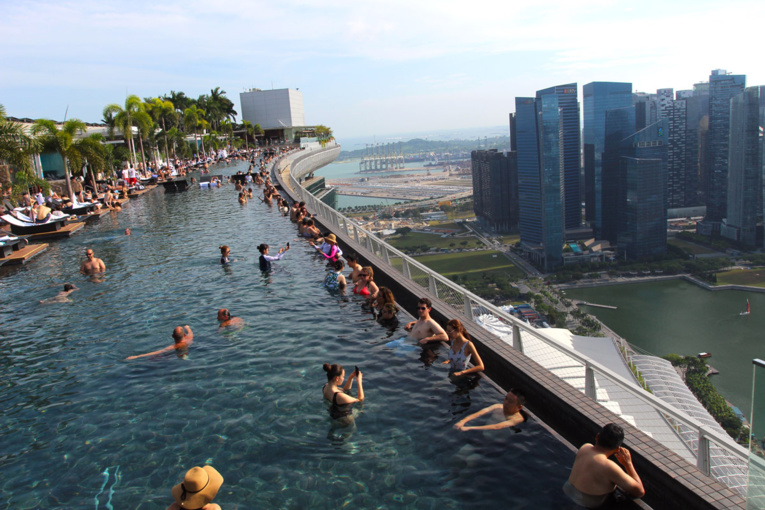 La piscine à débordement donne directement sur le quartier des affaires. C’est la plus longue piscine suspendue du monde, avec ses 146 mètres de long perchés à 191 mètres du sol (contenance : 1425 mètres cubes d’eau). La piscine à débordement donne directement sur le quartier des affaires. C’est la plus longue piscine suspendue du monde, avec ses 146 mètres de long perchés à 191 mètres du sol (contenance : 1425 mètres cubes d’eau).
