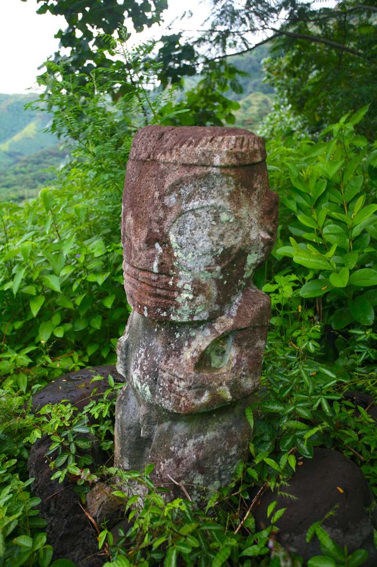 Le suberpe tiki couronné Moeone de Hanapaaoa, dominant le site où il se trouve, en pleine forêt. Le suberpe tiki couronné Moeone de Hanapaaoa, dominant le site où il se trouve, en pleine forêt.