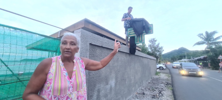 Faatini Cojan qui montre son fils Teano en train de recouvrir la croix de caducée avec un tissu noir. La mêche de la meuleuse s'étant cassée.