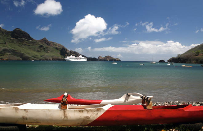 Une pirogue à balancier et le moderne paquebot “Paul Gauguin”, un des navires que les habitants de Nuku Hiva aimeraient voir plus souvent dans leurs eaux.