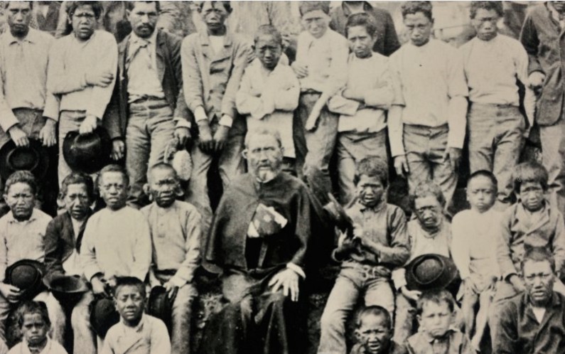 Damien entouré de ses petits lépreux, alors qu’il est lui-même très affaibli par la maladie. Il cessera le travail quinze jours avant sa mort seulement…