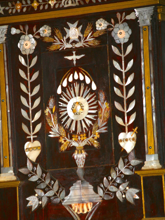 Trois couleurs de nacre (Pinctada margaritifera) ont été utilisées pour le tabernacle ; on remarque également à sa base un fragment de coquille de pu (Charonia tritonis).