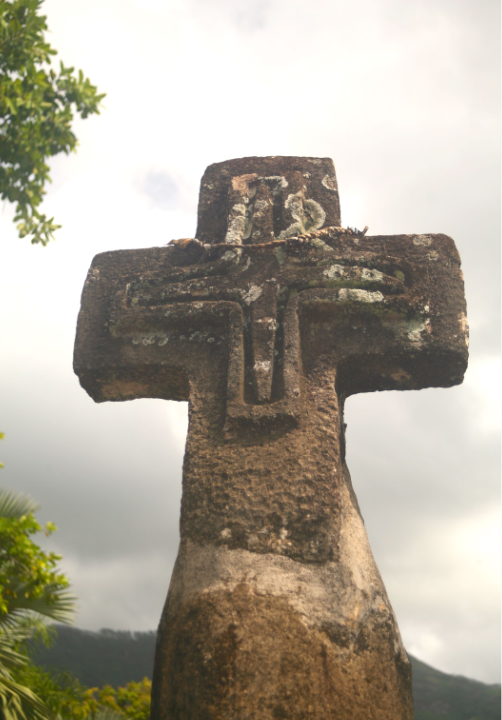 Une croix de pierre dressée sur la route du bord de mer indique l'entrée de la Mission catholique.