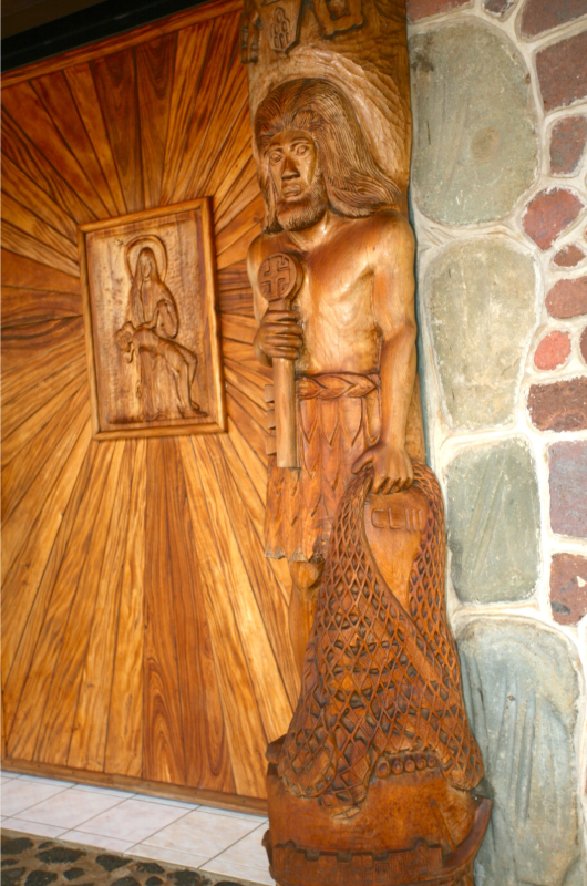 La porte d'entrée est composée de deux panneaux ; sur celui-ci Saint Pierre tient un filet avec 17 poissons.