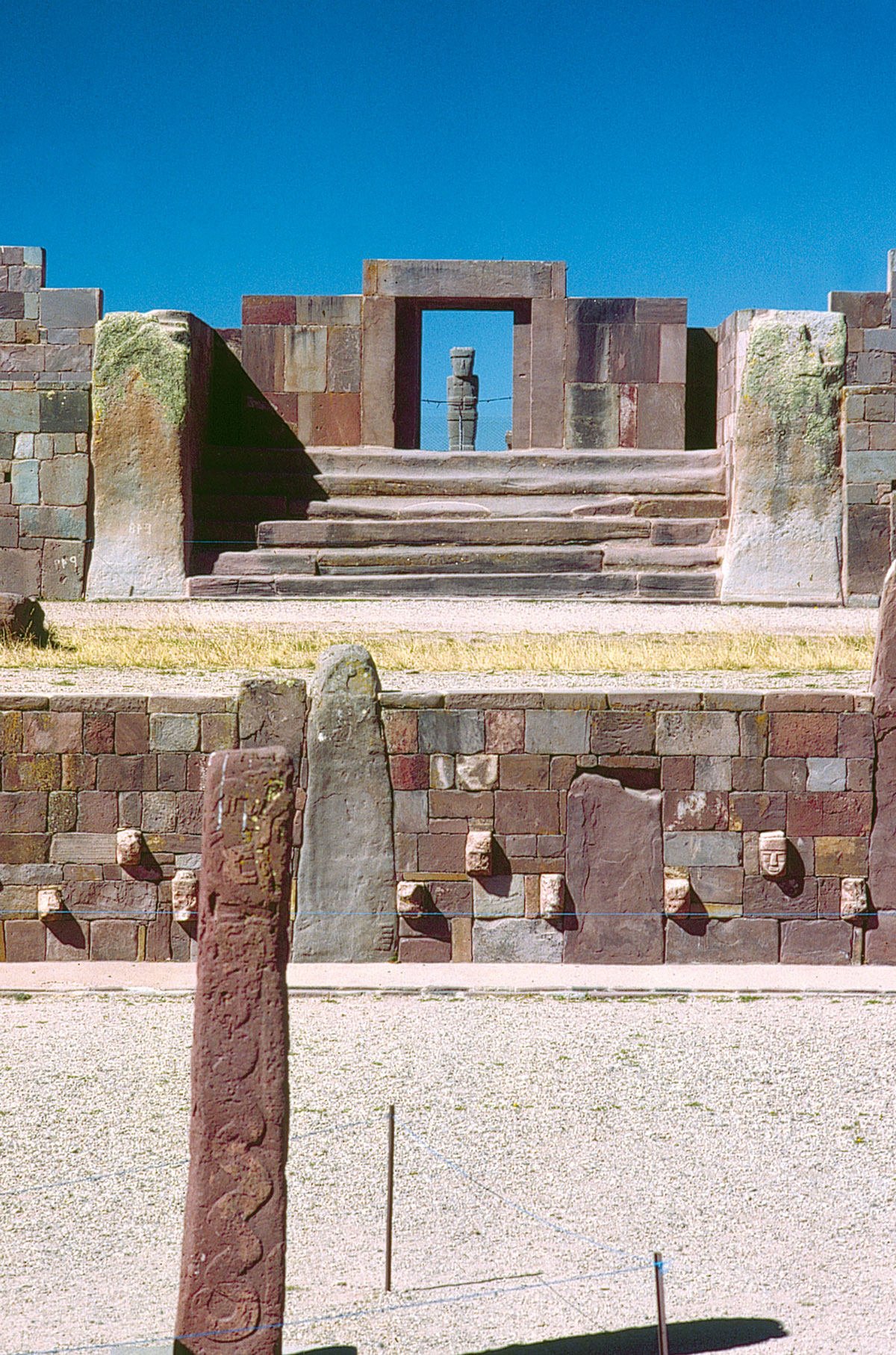 Le grand ensemble de Tiwanacu : en bas le Templete (vue partielle d'un mur de parement orné de têtes à tenon), à l'arrière-plan, escalier et portique d'accès au Kalasasaya, encadrant le monolithe “Ponce” (en grès).