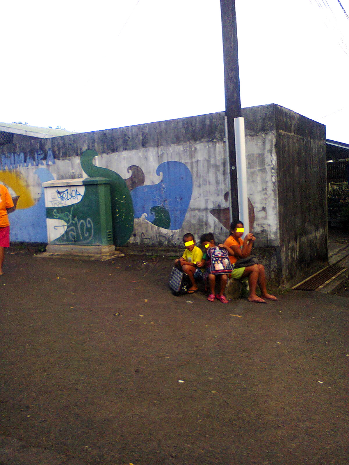 Des enfants attendent le bus scolaire, assis par terre et sans protection