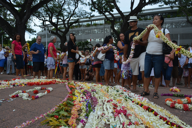 Un tapis de couronnes de fleurs déposé devant le monument aux morts.