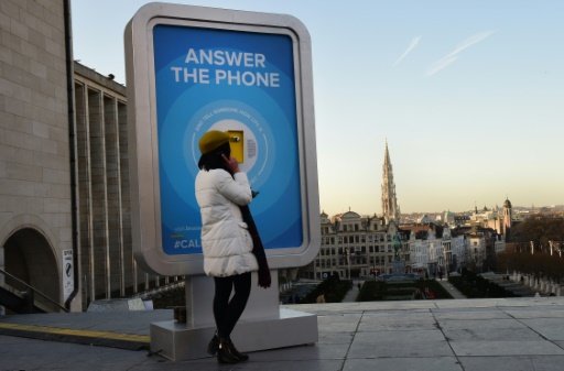 Une femme répond, le 8 janvier 2016, à un téléphone public installé à Bruxelles pour permettre aux gens d'interroger un habitant de passage pour obtenir des informations sur la sécurité de la ville