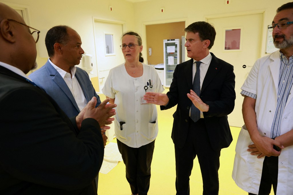 Le ministre français des Outre-mer Manuel Valls échange avec le maire de Saint-Paul Emmanuel Séraphin (2e à gauche) et des professionnels de santé, dont Karine Berny-Burlot (au centre) lors d'une visite au Centre Hospitalier Ouest Réunion au début de la campagne de vaccination contre le chikungunya, dans le cadre de son voyage de trois jours à La Réunion. Richard BOUHET / AFP