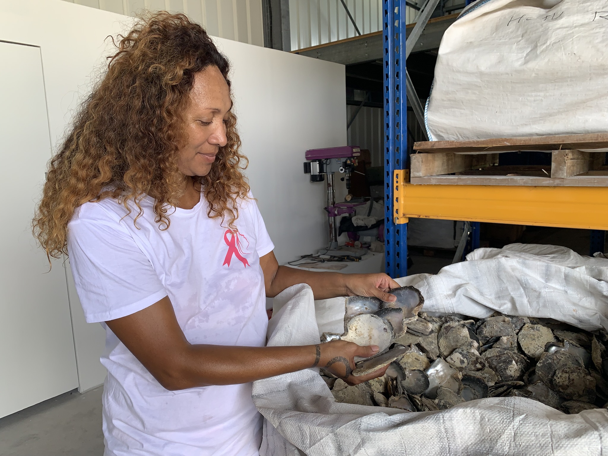 Mia Williams devant les nacres stockés dans les big bag ©Vaite Urarii Pambrun