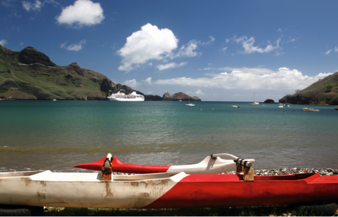 Une pirogue à balancier et le moderne paquebot “Paul Gauguin”, un des navires que les habitants de Nuku Hiva aimeraient voir plus souvent dans leurs eaux.