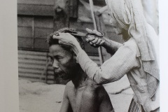 Une femme coupe les cheveux de sa voisine avec des ciseaux de tailleurs.